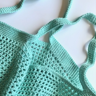 Duas sacolas de croché azul-turquesa em superfície branca