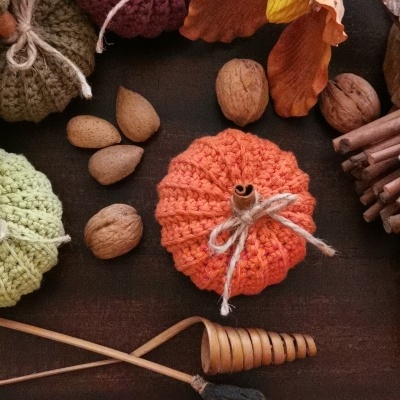 Abóboras de croché decorativas com nozes e paus de canela sobre madeira escura