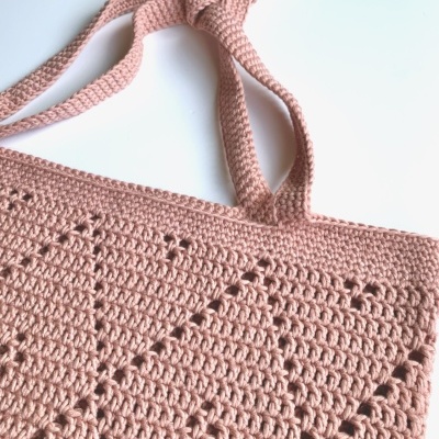 Mala em croché rosa claro com padrão triangular e alças em croché