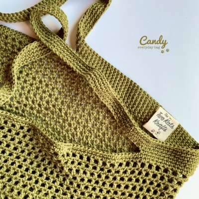 Saco de malha verde com alças e etiqueta 'Two Kits Knit' e texto 'Candy everyday bag' no fundo branco.