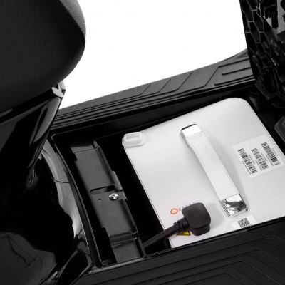 Bateria branca com alça num compartimento preto de scooter elétrica