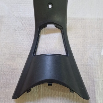 Suporte plástico preto triangular com abertura quadrada no centro sobre tecido bege acolchoado