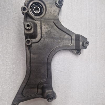 Peça metálica cinza com rolamento e quatro furos para fixação sobre fundo branco