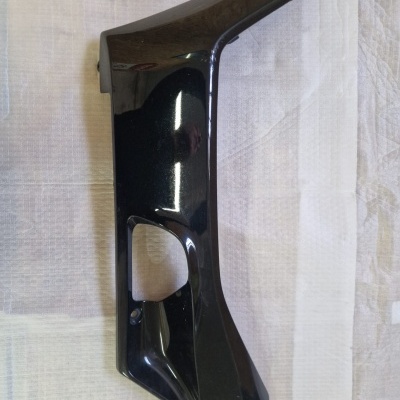 Peça preta de plástico com abertura colocada sobre tecido branco.