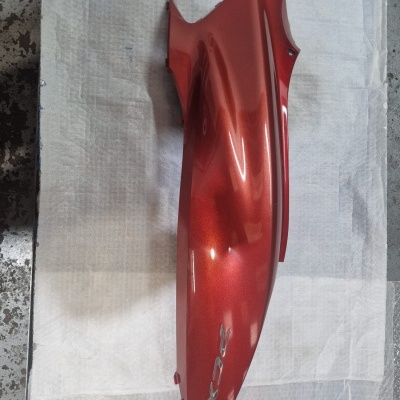 Peça lateral vermelha metálica de mota com texto X0R