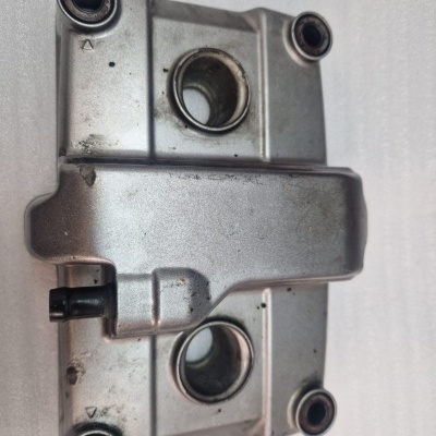 Peça metálica prateada robusta com quatro furos sobre fundo branco