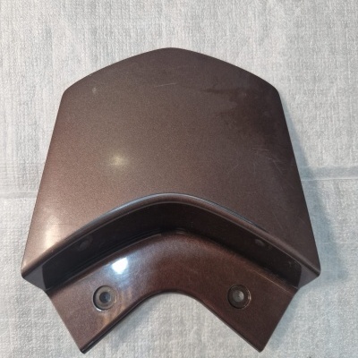 Peça de plástico castanha escura com curva e dois furos em superfície de tecido cinzento