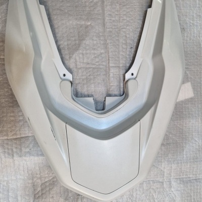 Peça plástica branca angular sobre superfície cinzenta