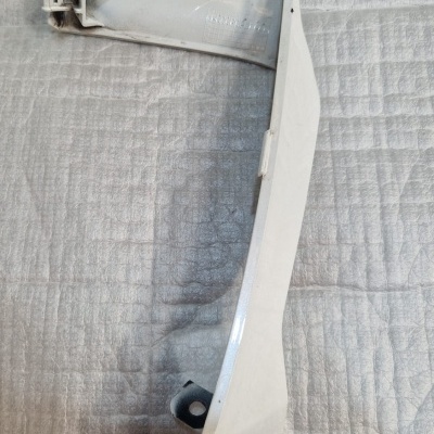 Peça plástica branca para automóvel sobre superfície acolchoada cinza