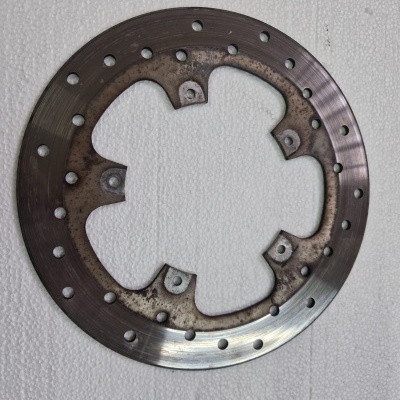 Disco de travão circular de metal com furos e sinais de uso sobre superfície branca