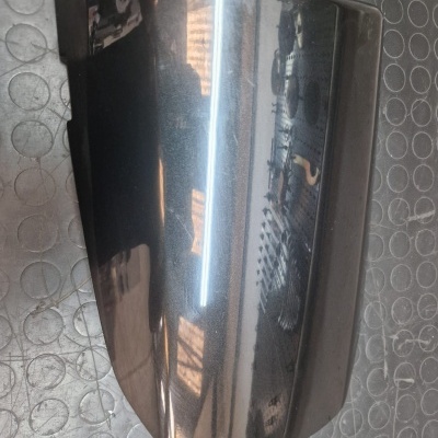 Tampa preta brilhante de mota sobre piso cinzento com padrão circular.