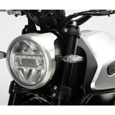 Detalhe do farol e parte frontal de motocicleta cinza e preta com a inscrição machan no farol