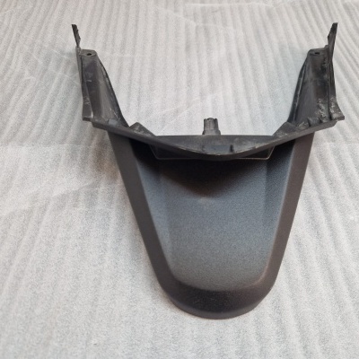 Peça plástica preta com textura lisa em tecido cinzento riscado