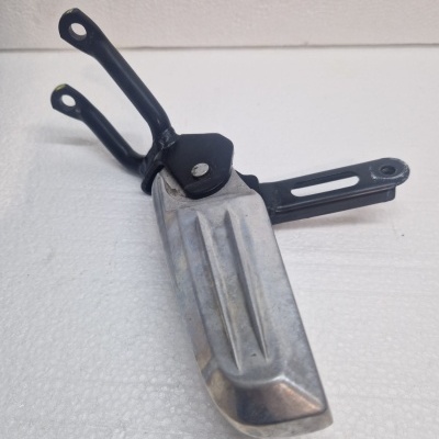 Pedaleira metálica prateada com suporte preto sobre superfície branca