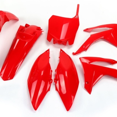 Peças plásticas vermelhas para motocicleta espalhadas sobre fundo branco