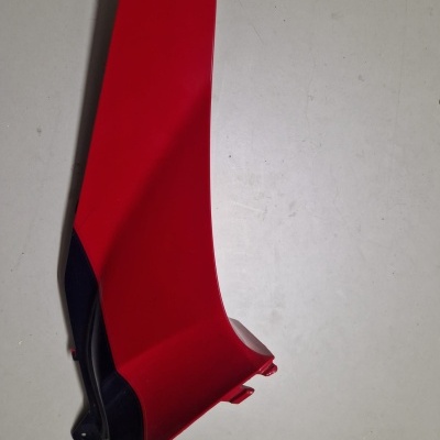 Peça plástica vermelha e preta com superfície lisa sobre fundo branco