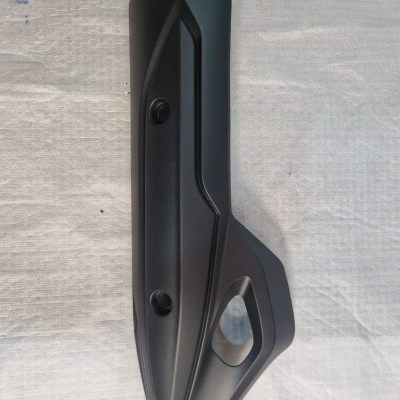 Protector de escape de motocicleta preto colocado sobre tecido claro