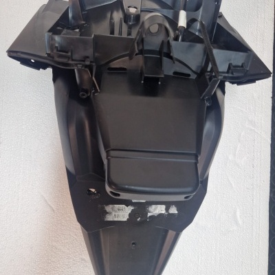 Peça plástica preta triangular com cabos, posição sobre superfície branca