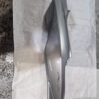 Peça cinza metálica de motocicleta sobre tecido branco