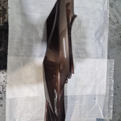 Peça de carroceria automóvel castanha metálica com acabamento brilhante sobre tecido e plástico