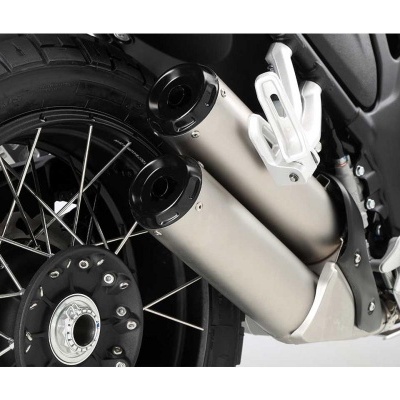 Escape duplo de motocicleta em metal prateado com tampas pretas perto da roda traseira