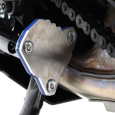 Peça metálica prateada junto a corrente de motocicleta e tubo de escape