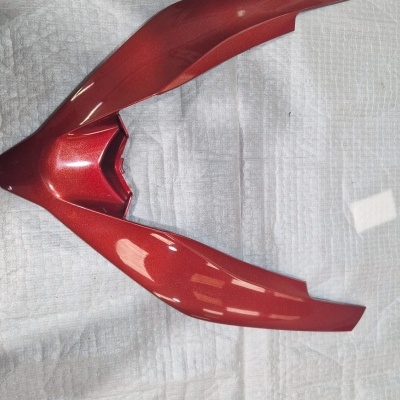 Peça de carenagem vermelha metálica para moto sobre pano branco