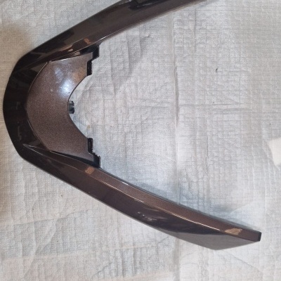 Peça arqueada castanho escuro com acabamento brilhante sobre tecido branco