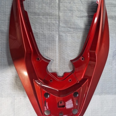 Peça plástica vermelha metálica para moto sobre tecido cinza