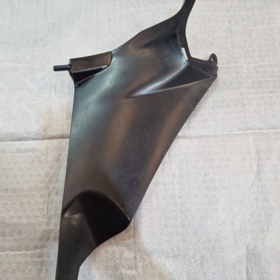 Peça automóvel preta em plástico sobre pano branco