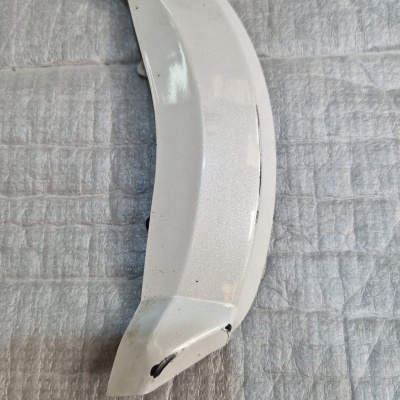 Peça metálica curva branca sobre tecido cinzento acolchoado