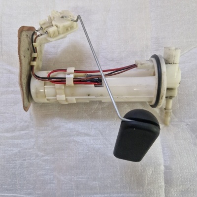 Peça automóvel plástica com esfera preta e filtro castanho sobre superfície clara