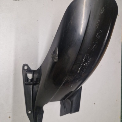 Peça plástica preta com sinais de desgaste sobre fundo branco