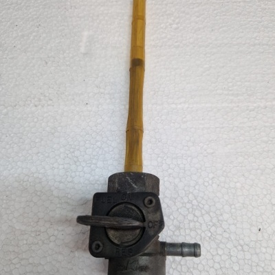 válvula de combustível metálica com tubo plástico amarelo sobre fundo branco