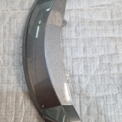 Peça metálica prateada curva sobre tecido branco acolchoado