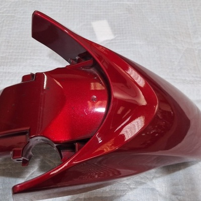 Peça de plástico vermelho brilhante com design aerodinâmico sobre tecido branco