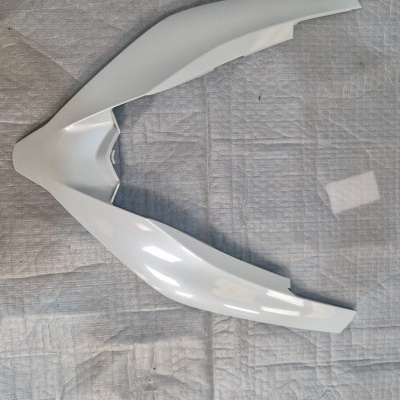 Peça plástica branca angular sobre tecido cinzento acolchoado