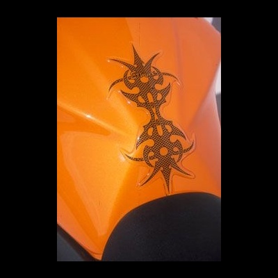 Detalhe de capacete ou veículo laranja metálico com decalque tribal preto