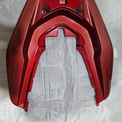 Peça plástica vermelha metálica angular sobre tecido branco