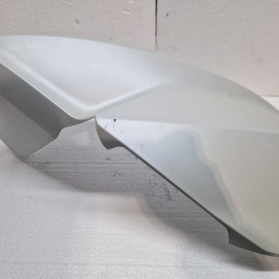 peça plástica cinza claro fosca com formato assimétrico em superfície branca