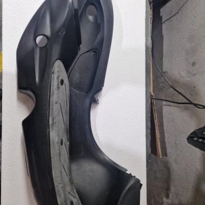 Peça plástica preta sobre superfície branca numa sala interna