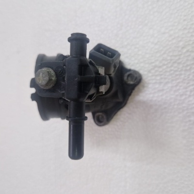 Válvula automóvel preta com conector elétrico sobre superfície branca