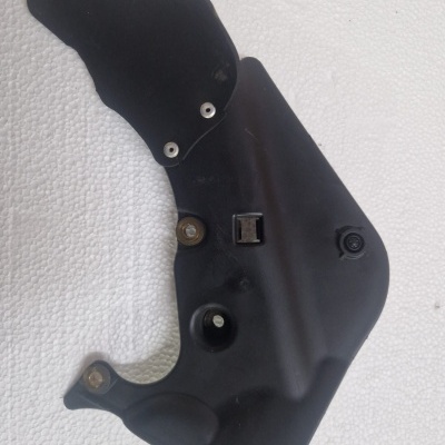 Componente automóvel preto com parafusos sobre fundo branco texturizado