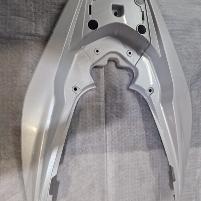 Peça plástica branca para moto sobre tecido cinzento