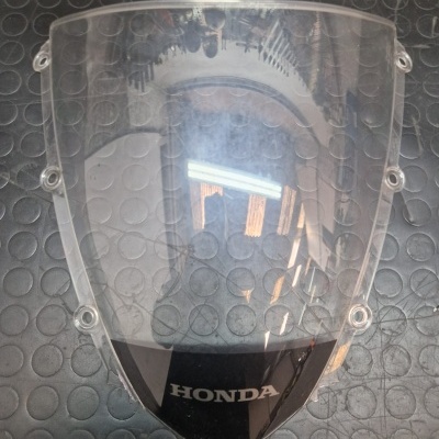 Para-brisas transparente com logótipo HONDA sobre superfície preta circular