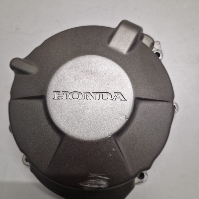 Tampa de motor de motocicleta Honda em metal cinzento com logótipo gravado.