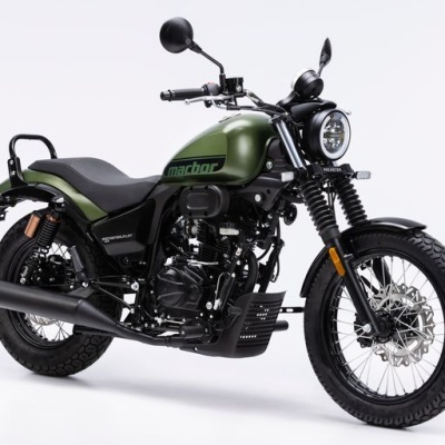 Motocicleta verde militar com farol redondo, pneus mistos e marca machor no depósito