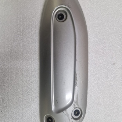 Puxador metálico prateado com três furos para parafusos e riscos visíveis.