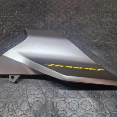 Peça de carenagem cinza metálica para moto com texto amarelo HORNET