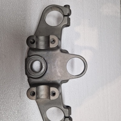 Peça metálica cinzenta com orifícios circulares e parafusos